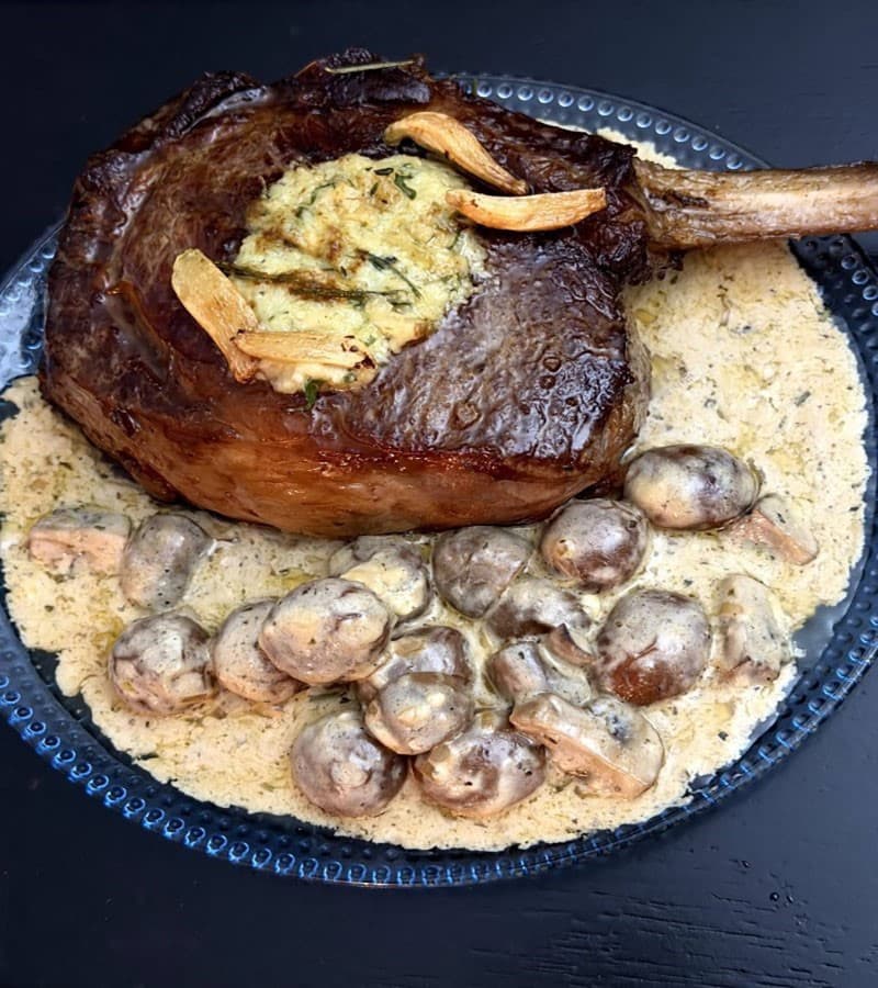 A tomahawk ribeye finished with garlic butter, over a mushroom cream sauce